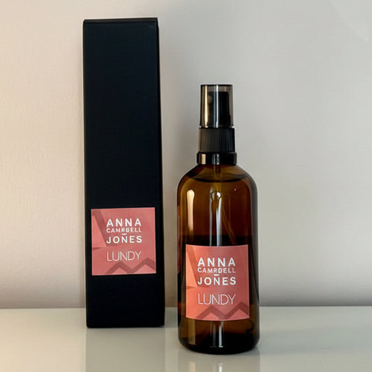 linen mist, fabric freshener, room spray in Brown bottle with pink label and black box on a light gray background 